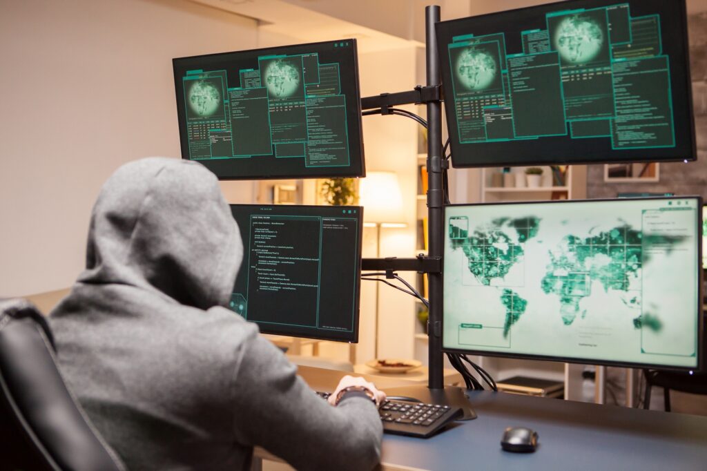 Dangerous hacker wearing a hoodie while planting a malware