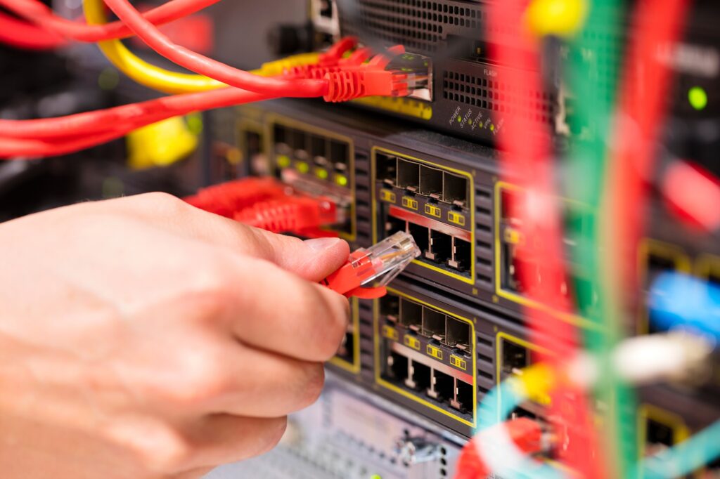 IT consultant connects a network cable into switch in datacenter