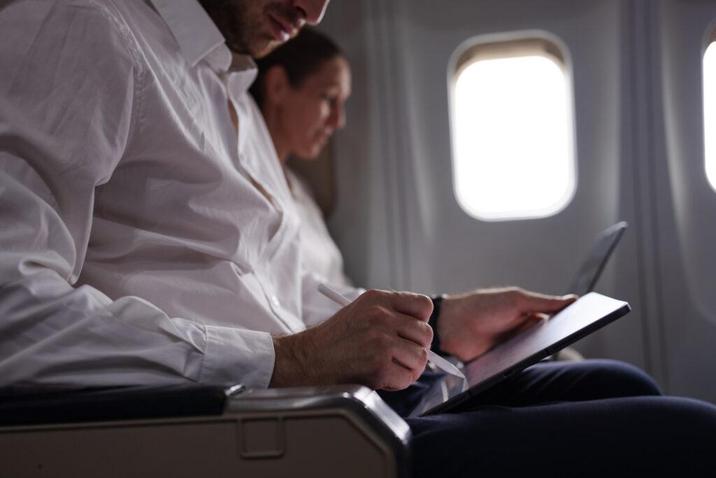 Business Professionals Using Digital Devices on Airplane Seats During Flight